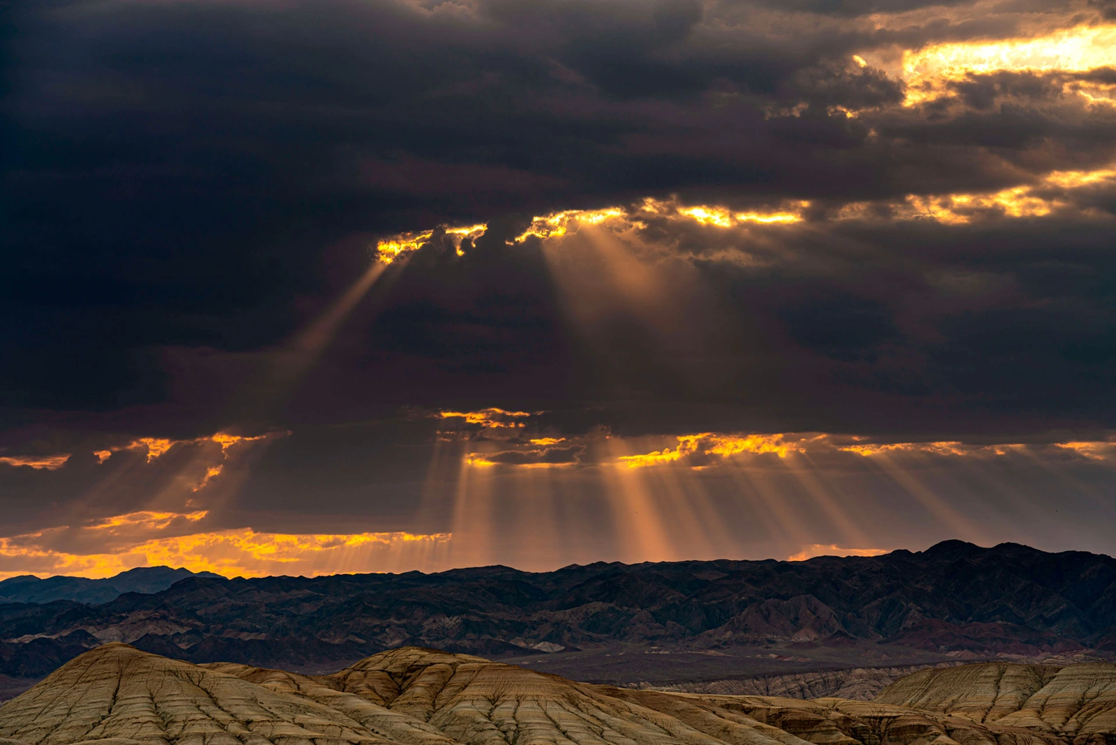 Sun rays breaking through storm clouds over the Aktau Mountains at dusk